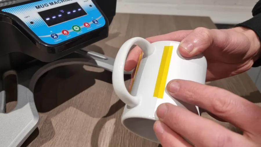 A professional using a mug heat press to customize mugs