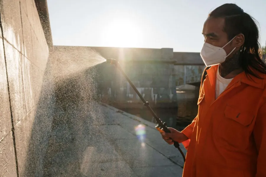 man using pressure washer on wall