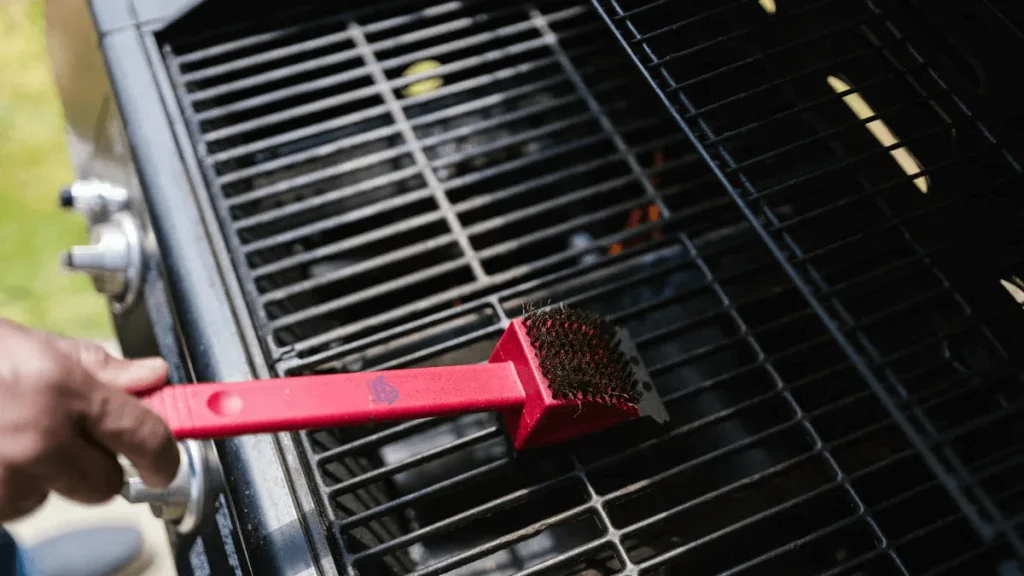 Person cleaning grill with brush