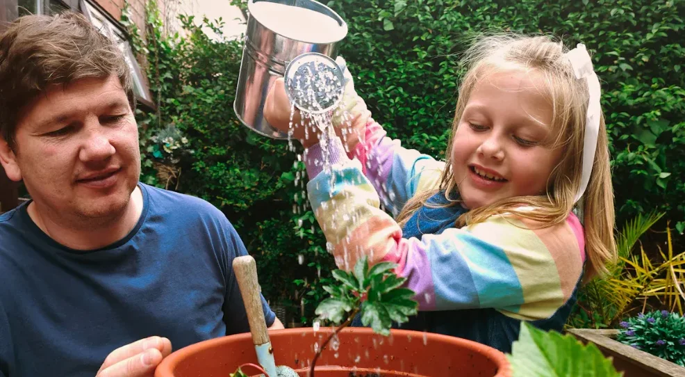 A father and his daughter watering a plant