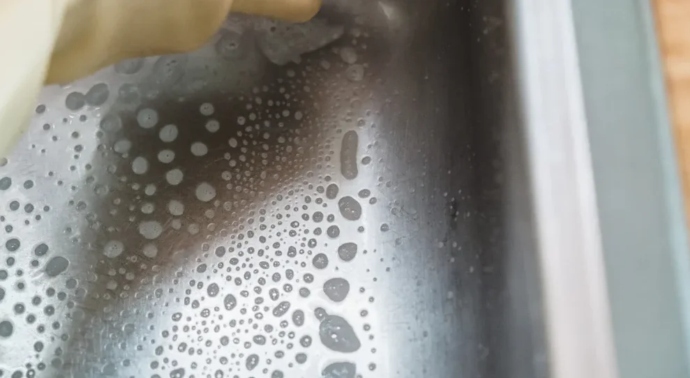 A close up of a metal dish being washed