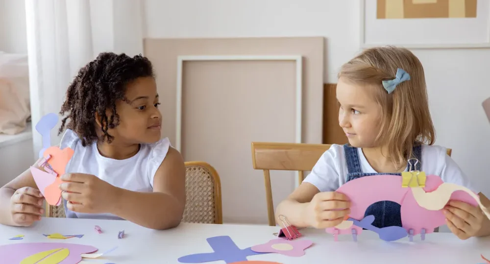 Two kids making paper objects
