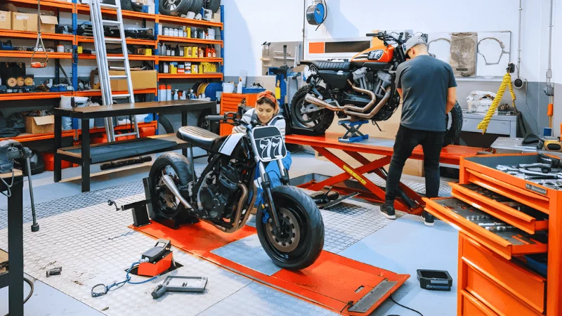 Mechanics repairing motorcycles in garage