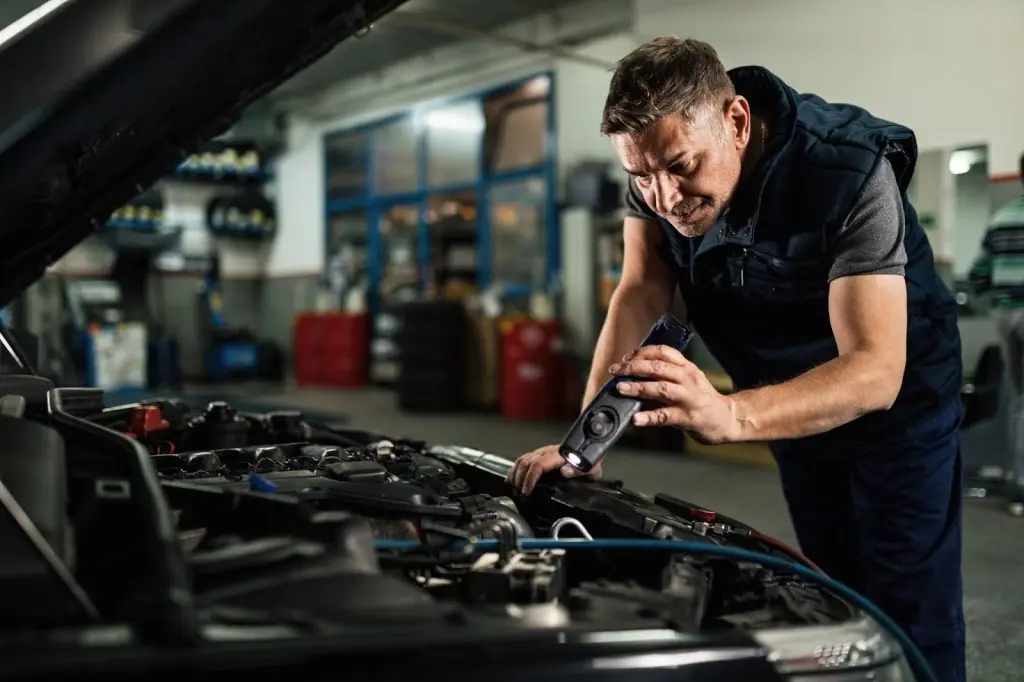 man looking at the engine of a car