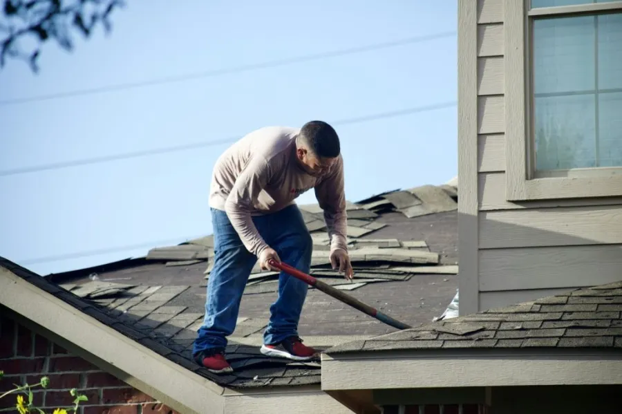 man cleaning roof debris
