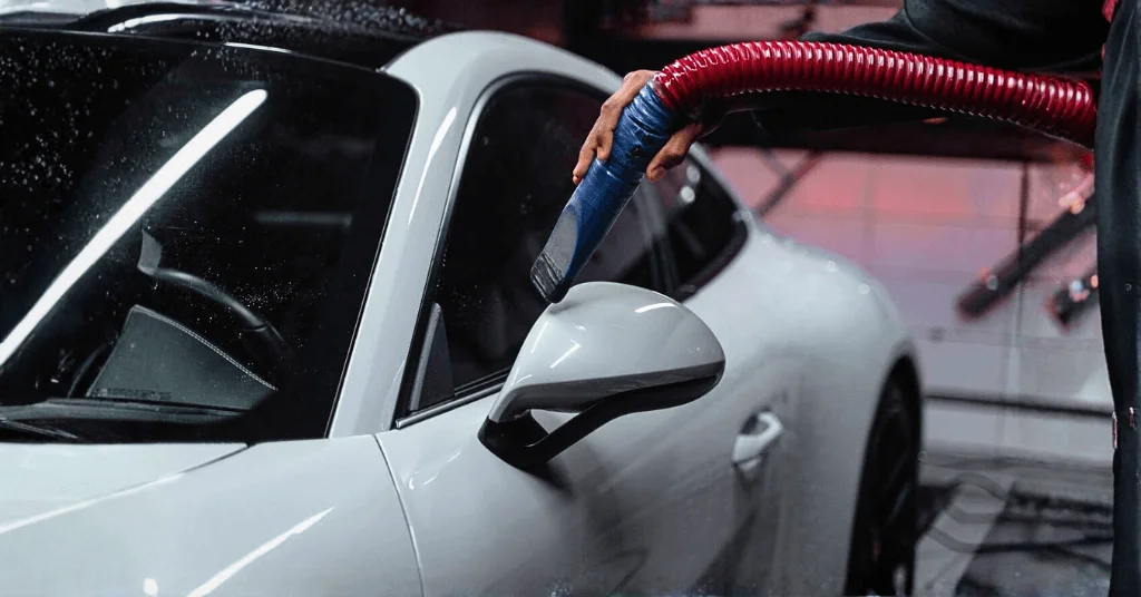 portable vacuum cleaner is used to suck dust from a car