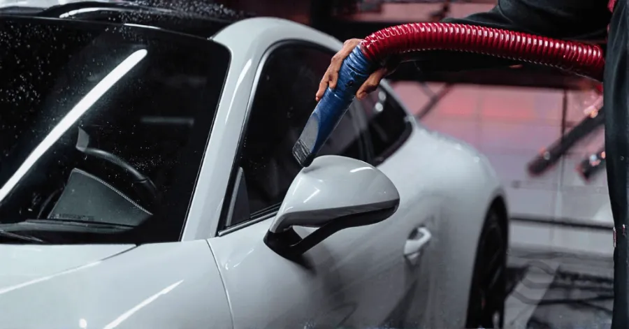 portable vacuum cleaner is used to suck dust from a car