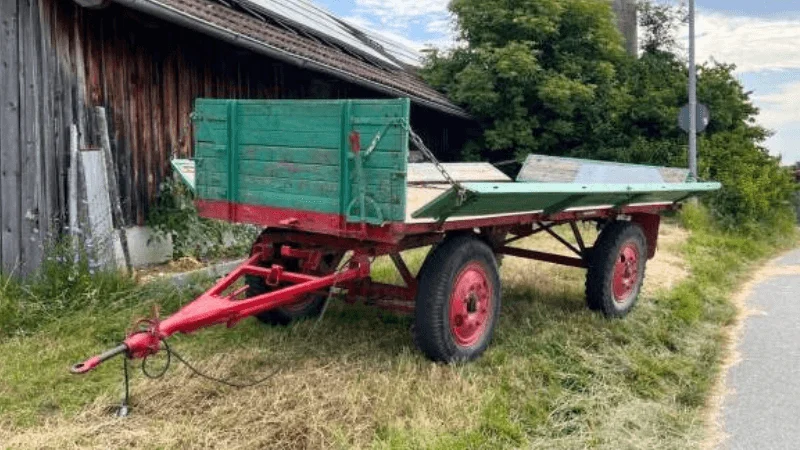 A utility trailer parked outside a shed at home