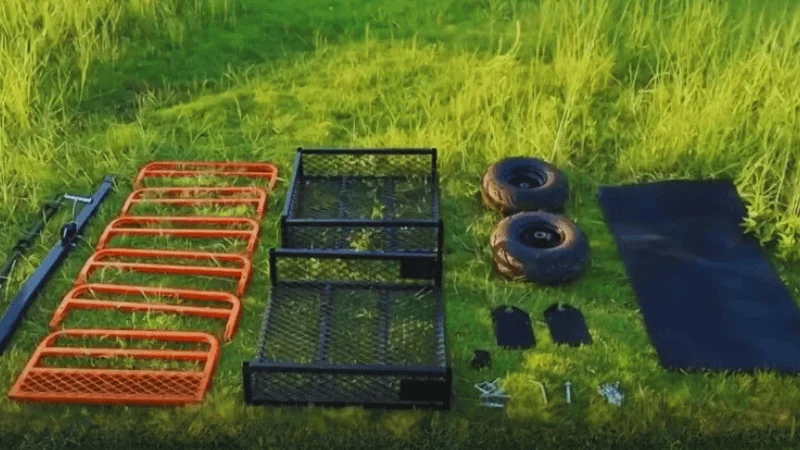 Different ATV Dump Trailer parts are arranged on the ground