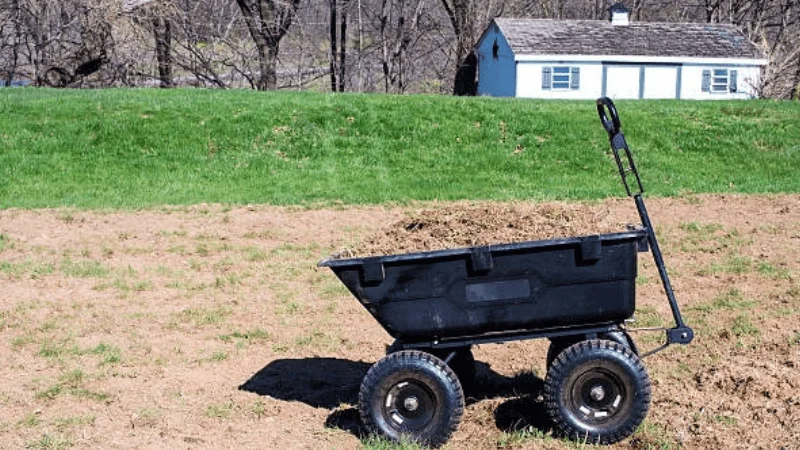 four-wheeled garden trailer cart is being used to haul soil on a farm