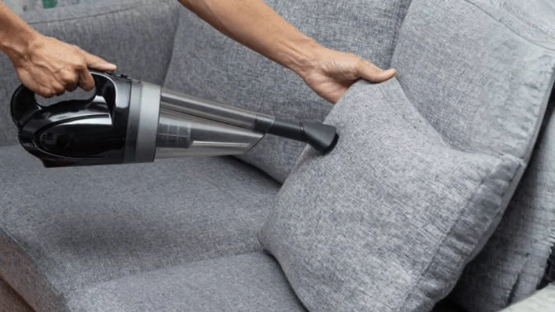 handheld cordless vacuum cleaner is being used to clean cushions