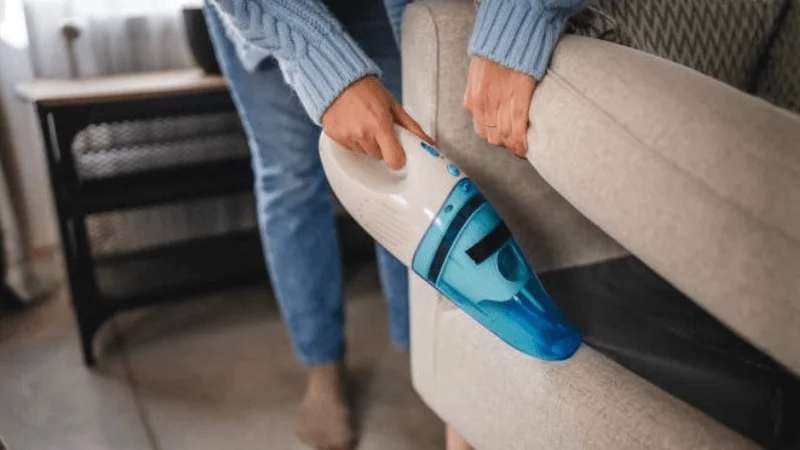 lady cleaning sofa seat using a portable vacuum 