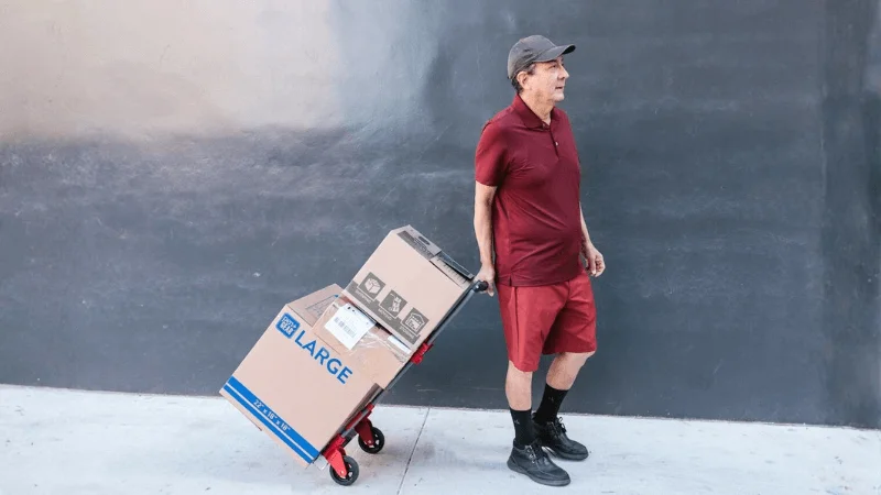 senior employee dragging cargo boxes on a service utility cart