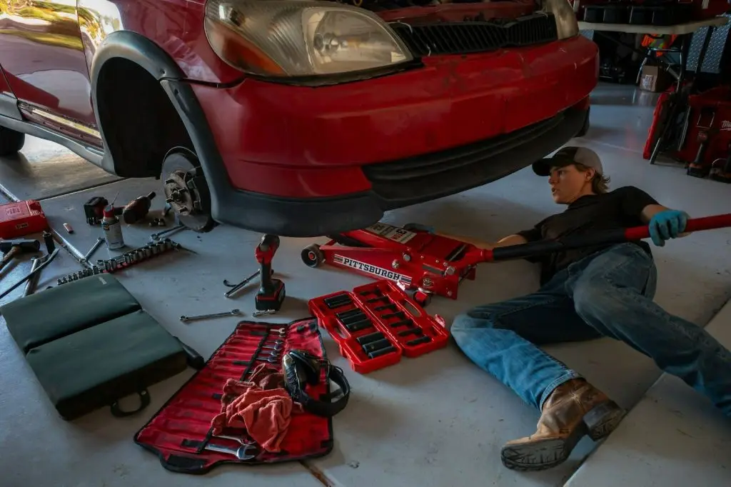 A professional mechanic is inspecting the undercarriage and suspension components of a modern vehicle in a garage