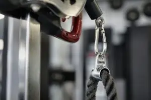 A close-up view of a gym cable and pulley system being inspected for wear and tear