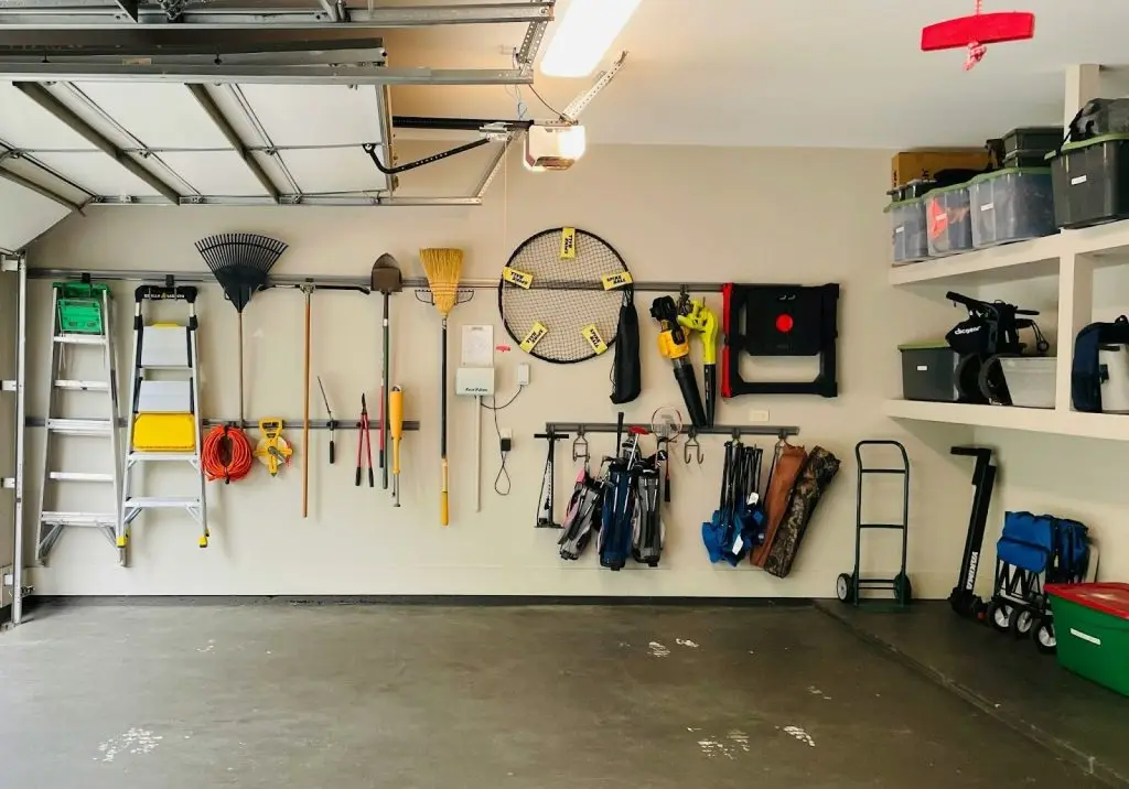 A clean and organized garage featuring various lawn tools hanging neatly on a pegboard​