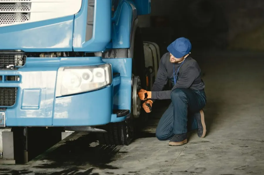 Close-up of a person checking the tread and lug nuts of a truck tire for a truck maintenance checklist update.