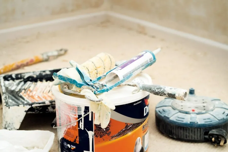 A professional-grade caulking gun is lying on top of a paint can.