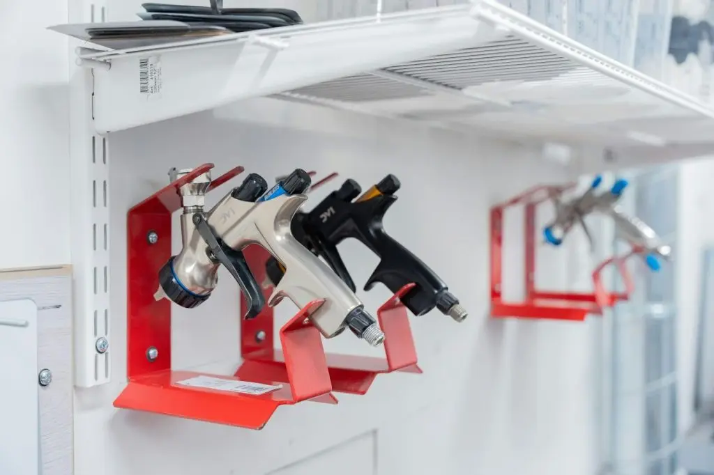 A variety of plastic caulking gun extension nozzles are arranged on a tool wall.