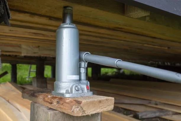 A bottle jack being used at a construction site to lift a floor.