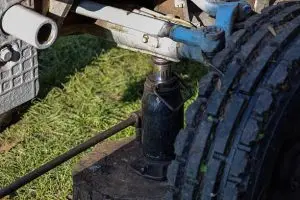 A bottle jack being used to lift a vehicle chassis