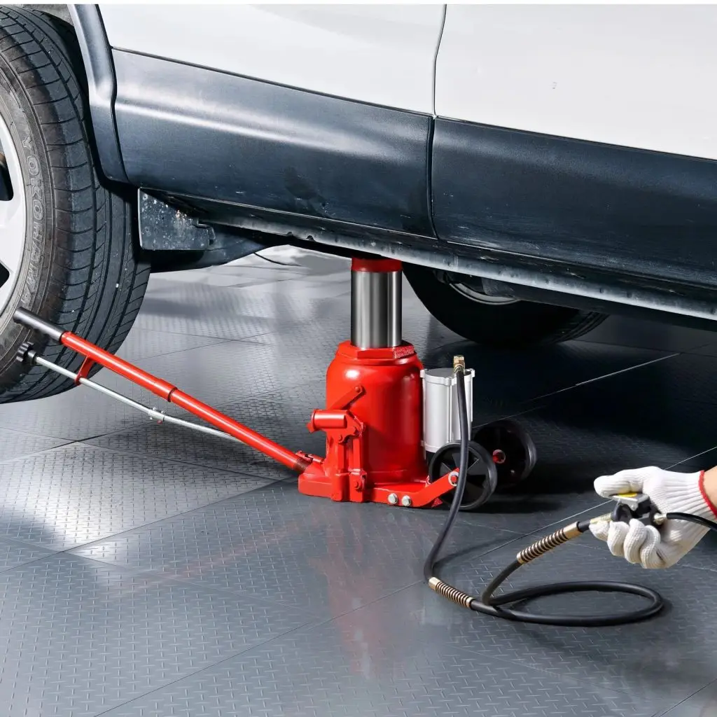 A manual and pneumatically controlled bottle jack being used in a garage