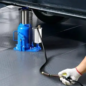 A pneumatic bottle jack being used to lift a car in a garage