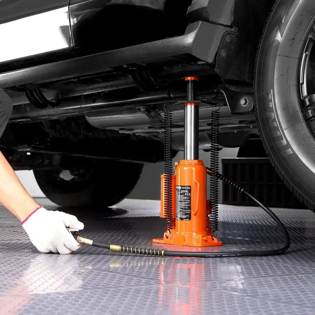 A worker pressing the manual air pump to operate a bottle jack