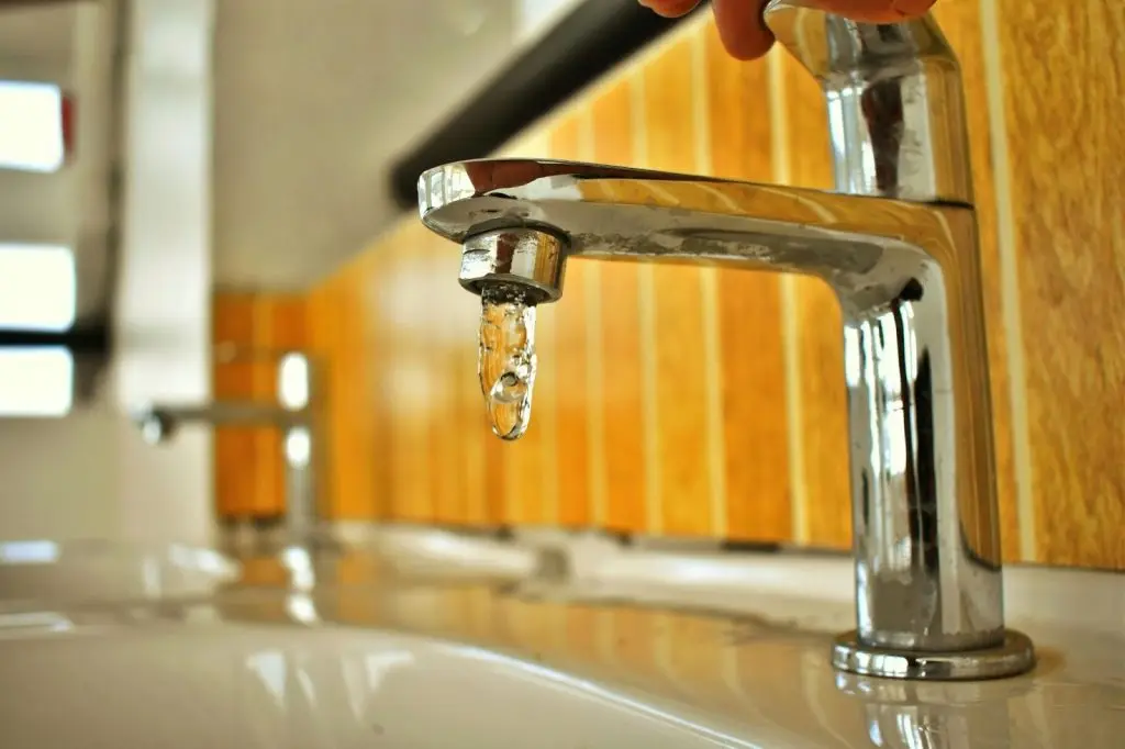 Eine Nahaufnahme eines einzelnen Wassertropfens, der aus einem Wasserhahn fällt.