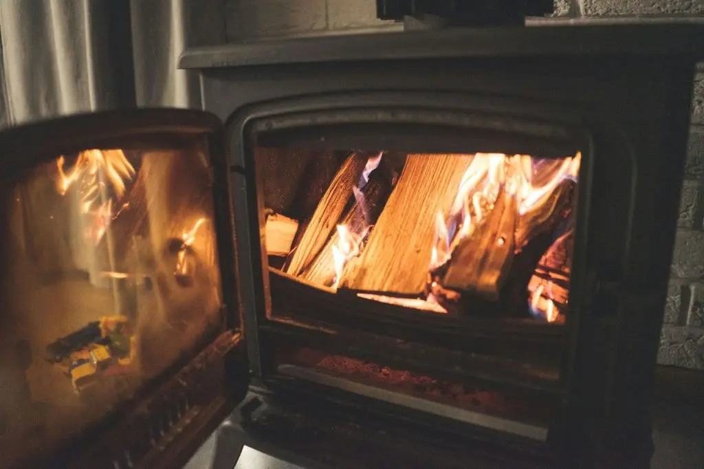 A black metal safety gate standing in front of a fireplace with a lit fire.
