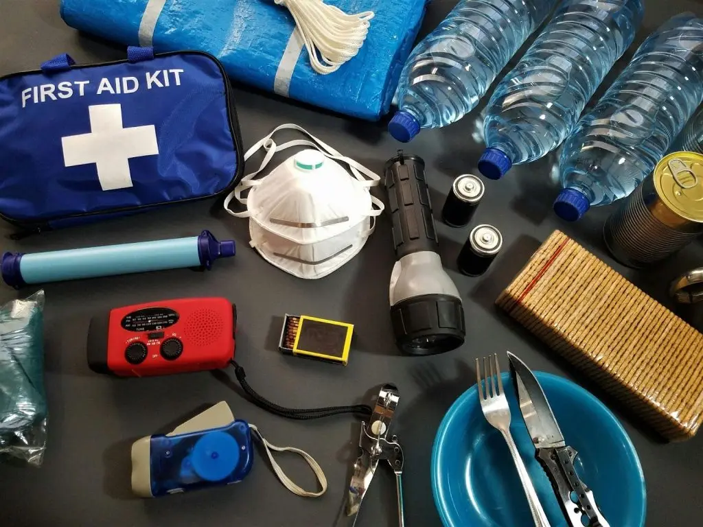 A close-up shot of an organized winter emergency kit including a flashlight, first aid supplies, and water bottles.