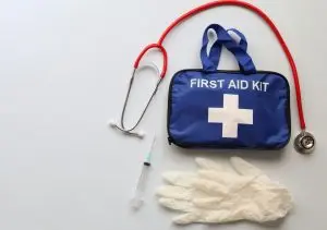 A close-up shot of a first aid kit, medical gloves and a stethoscope on top of the kit