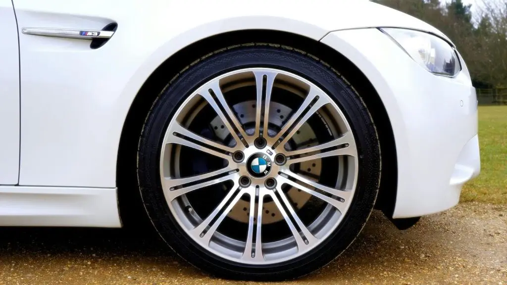 A close-up shot of a car tire on a rainy, wet road