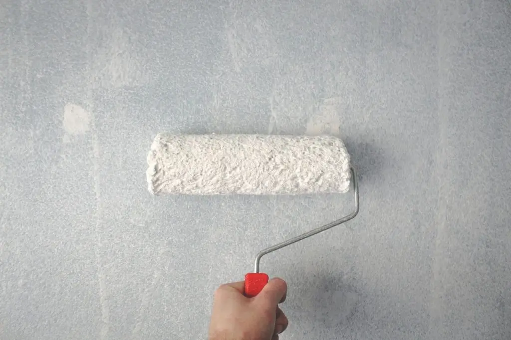 rolling white paint on a wall
