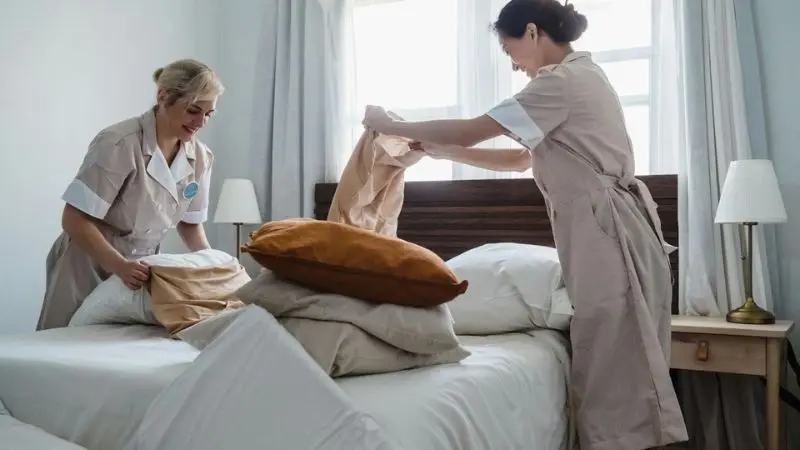 staff changing linens in a hotel room
