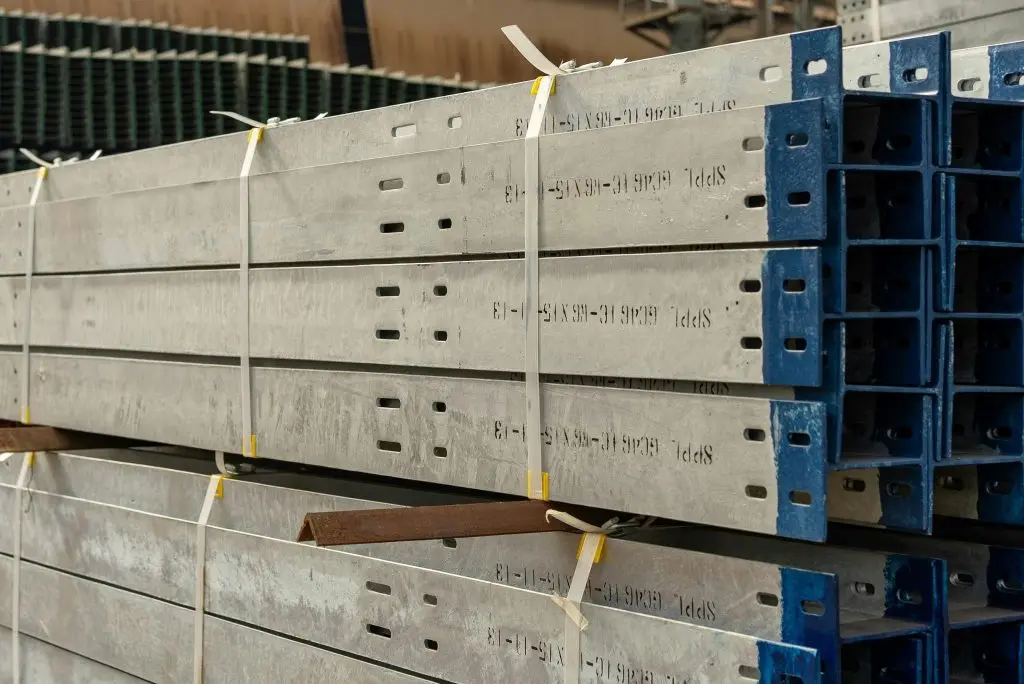 A stack of several gray steel beams piled on top of each other at a construction site.