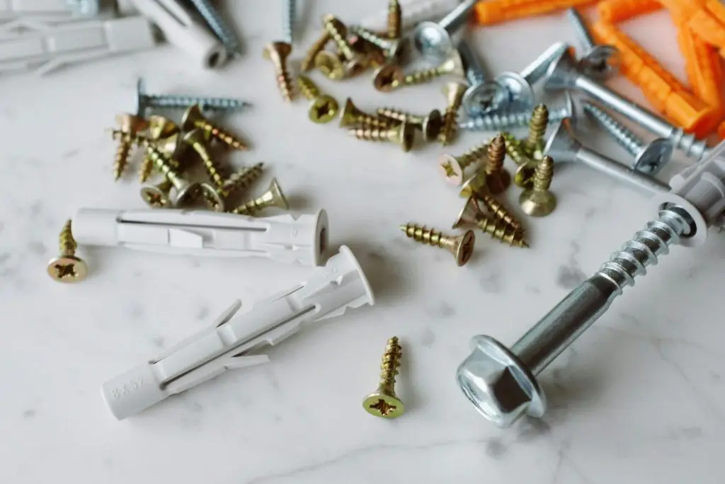 Anchor Bolts and nails scattered over a white marble