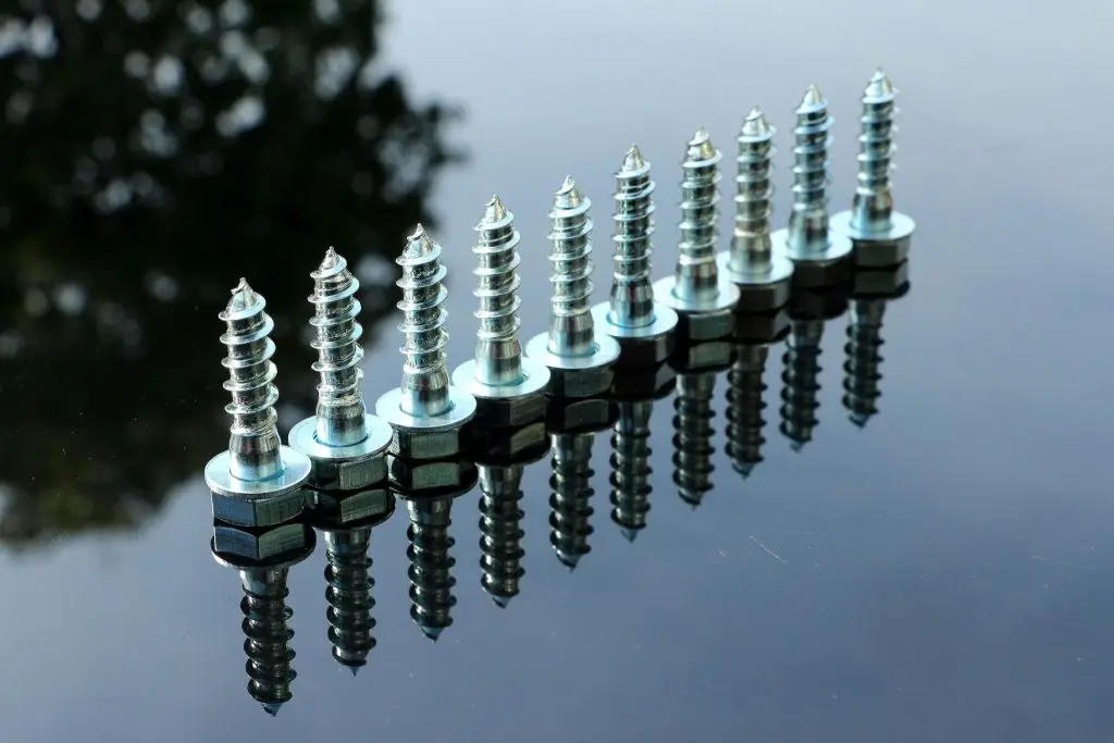 Different kinds of plow bolts are set upside down on a flat area.