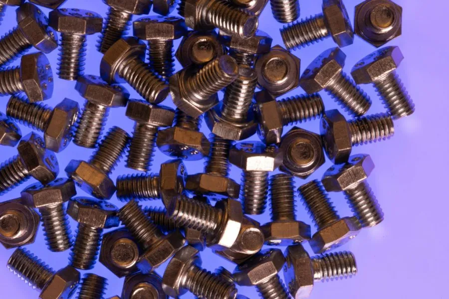 Numerous steel plow bolts are dispersed over a level blue surface.
