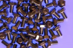 Numerous steel plow bolts are dispersed over a level blue surface.