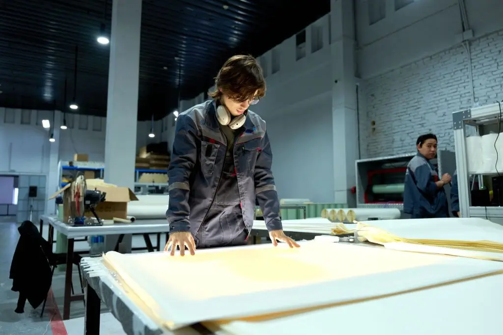 A factory worker looking closely at vapor retarder sheets. 