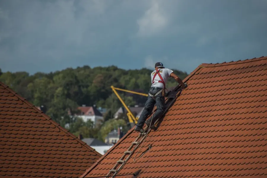 A man climbed over the roof using the stairs to repair it. 