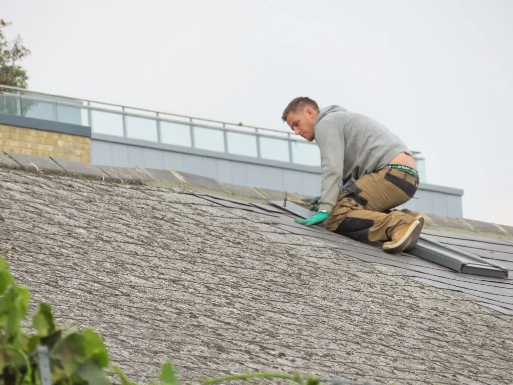 A close-up of a man on a roof discovering the cause of the leakage. 
