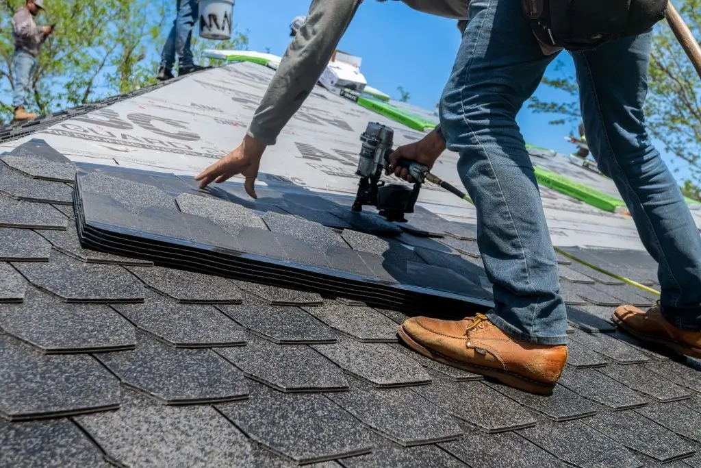 A guy applies a protective sheet to the roof to patch the leak.