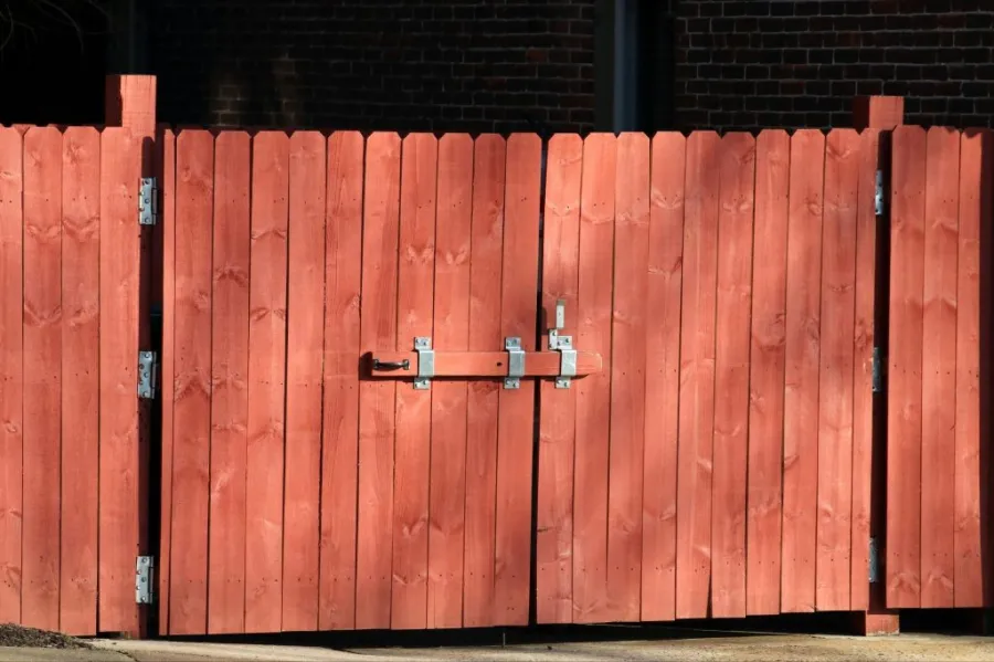 Rustic red wooden fence with a metal latch