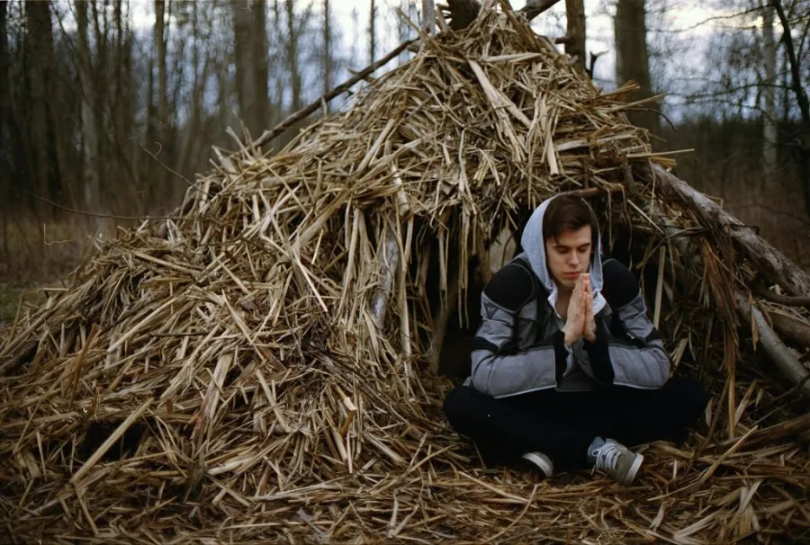 Guy sitting inside a man-made emergency shelter