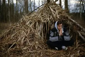 Guy sitting inside a man-made emergency shelter