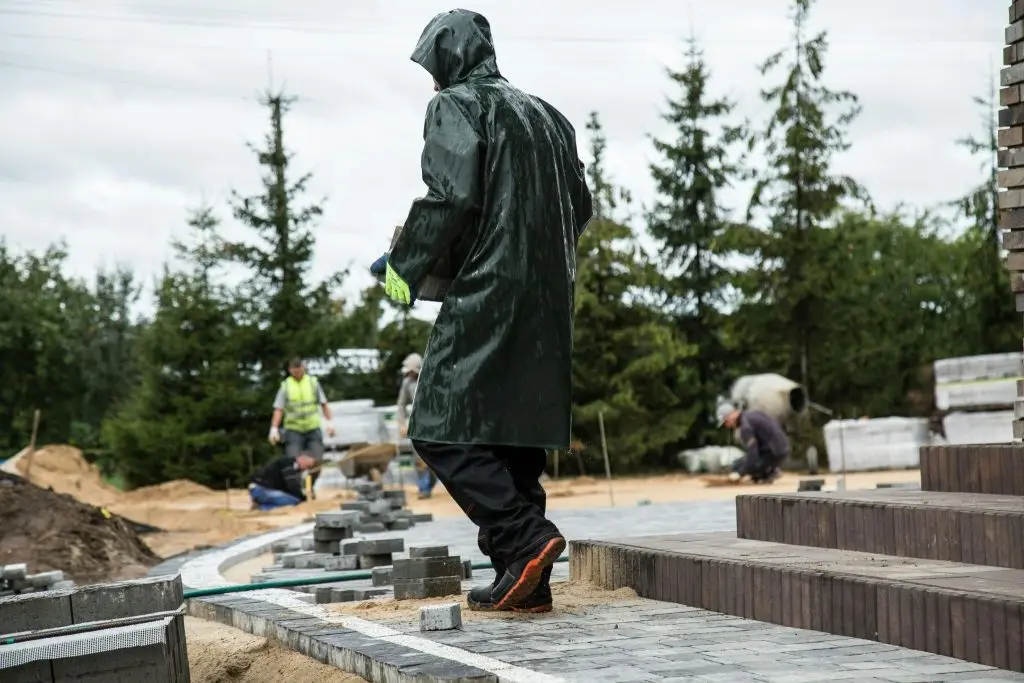 Worker in raincoat laying pavement