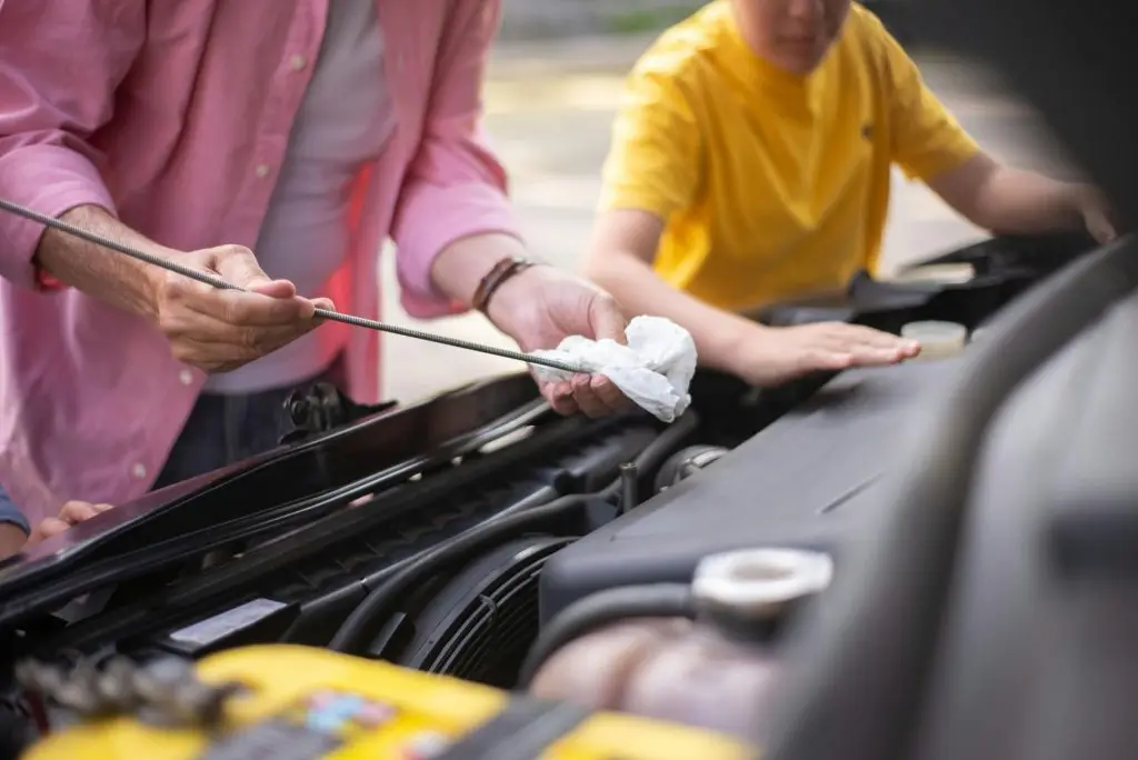 A close up view of a man and a boy repairing a car engine with a wrench.