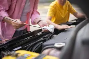 A close up view of a man and a boy repairing a car engine with a wrench.